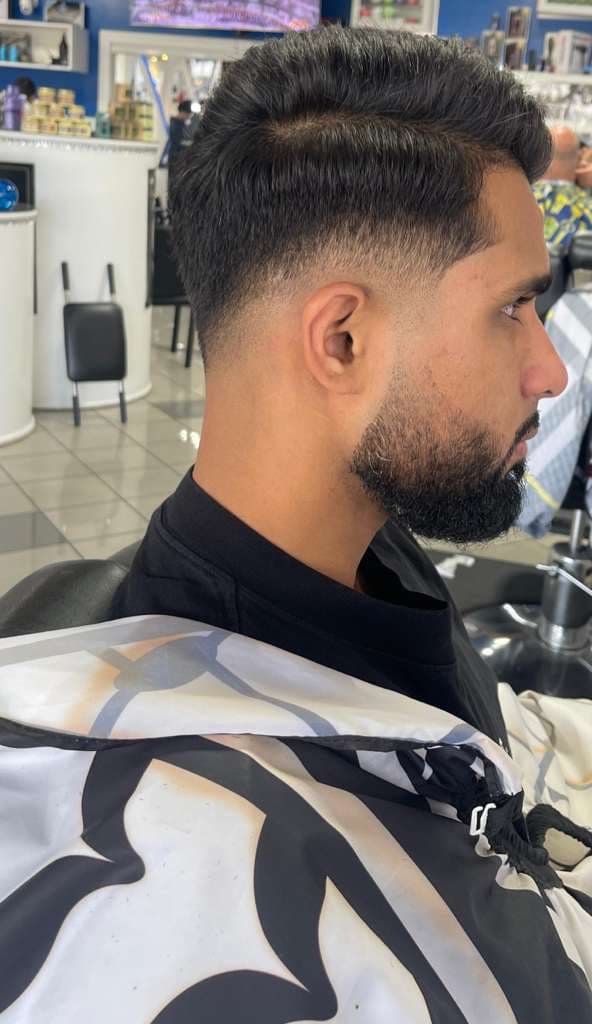 Profile view of a mid-fade haircut and groomed beard